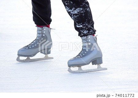 feet on the skates of a person rolling on the ice rink 74011772