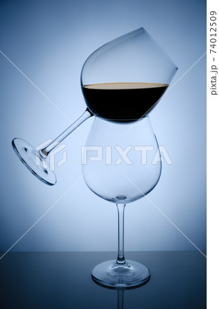 Two wine glasses on mirrored surface over white background, studio advertising shot, copy space 74012509