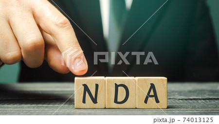Wooden blocks with the word NDA - Non disclosure agreement. A legal contract entered into by two parties with limited access to third parties. Business concept Wooden blocks with the word NDA - Non disclosure agreement. A legal contract entered into by two parties with limited access to third parties. Business concept 74013125