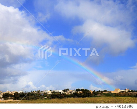 ヨーロッパ 雨の晴れ間に虹のかかる田舎の風景の写真素材