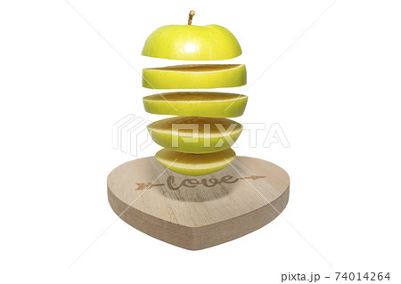 A stack of green apples falls or flies over a heart-shaped board.Creative food levitation A stack of green apples falls or flies over a heart-shaped board.Creative food levitation 74014264