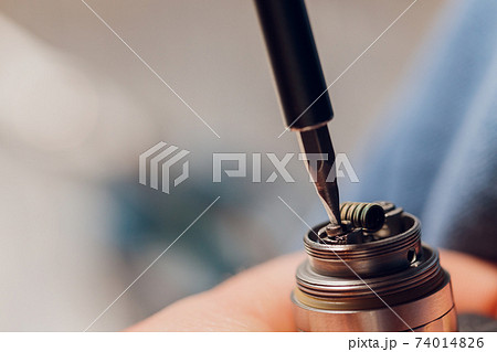 Specialist replaces spring for smoking vape.Professional maintaining electronic cigarette in shop.Fix broken vaping device and quit smoking nicotine cigarettes. 74014826