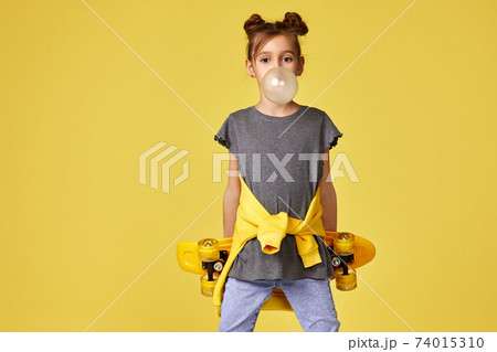 child girl with skateboard blowing a big bubble gum 74015310