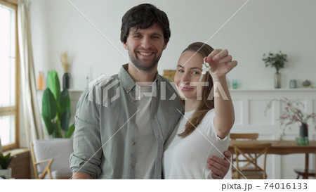 Young couple holds happily a key to their new home Young couple holds happily a key to their new home 74016133