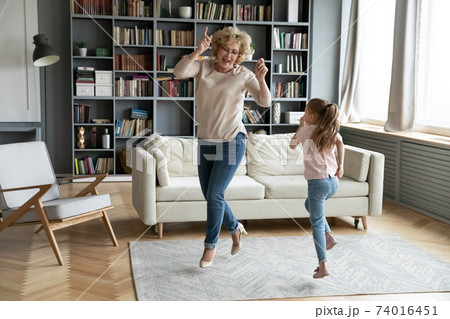 Overjoyed mature senior grandmother dancing with little girl. 74016451