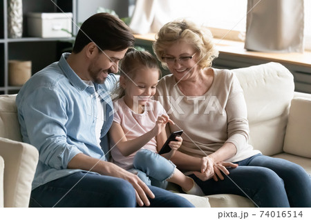 Happy different generations family using smartphone at home. 74016514