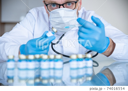 Doctor in the laboratory in medical mask and gloves prepares vaccines for coronavirus. Doctor in the laboratory in medical mask and gloves prepares vaccines for coronavirus. 74016554