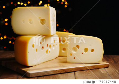Cheese on table on the dark background. Medium hard cheese head edam, gouda, parmesan on wooden board. Healthy eating concept. 74017440