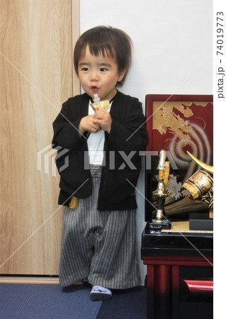 5月5日端午の節句のとき兜飾りの横に立ってジュースを飲む2歳の男の子 5月5日端午の節句のとき兜飾りの横に立ってジュースを飲む2歳の男の子 74019773