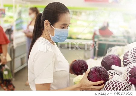 Asian woman long hair wearing protective face mask  in supermarket department store. Female, looking grocery to buy  some fruit. New normal after covid-19. Family concept. 74027910