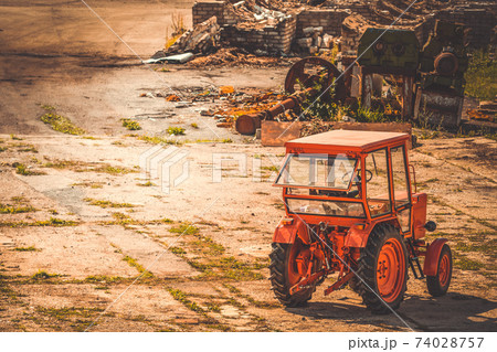 Tractor parked in the yard of abandoned factory Tractor parked in the yard of abandoned factory 74028757
