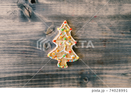 Traditional festive gingerbread cookies in the shape of a Christmas tree on a wooden board. 74028991