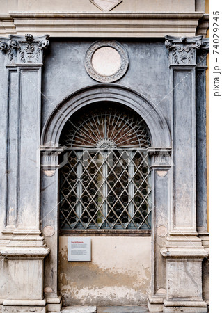 Arched window with a metal lattice in the opening between the columns with patterns. 74029246