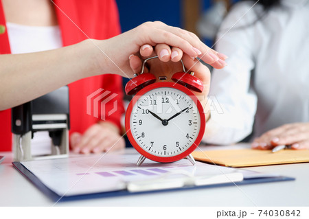 Two business women turning off alarm clock at workplace closeup Two business women turning off alarm clock at workplace closeup 74030842