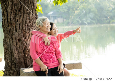 Happy old elderly woman and child girl laughing,embracing in outdoor park on sunny day,loving senior grandmother,smiling teenage granddaughter enjoy, relax on holiday together,health care,generation,l Happy old elderly woman and child girl laughing,embracing in outdoor park on sunny day,loving senior grandmother,smiling teenage granddaughter enjoy, relax on holiday together,health care,generation,l 74031422