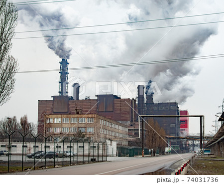 Dense thick smoke comes from industrial chimney pipes. Pipes with smoke, industrial production 74031736