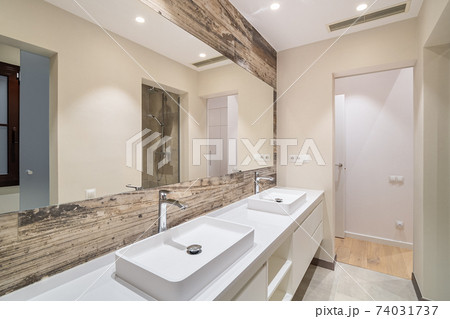 Modern tiled bathroom with a shower area, two sinks and a big wall mirror 74031737