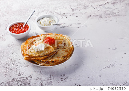 Stack of russian pancakes blini with red caviar, fresh sour cream 74032550