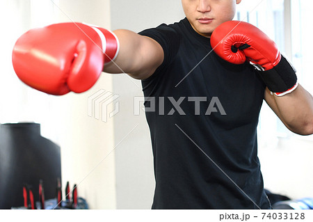 ボクシンググローブをつけてパンチを打つ若い男性の写真素材