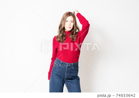 白い壁の前に立って、ポーズをとる赤いセーターを着た若い女性 白い壁の前に立って、ポーズをとる赤いセーターを着た若い女性 74033642
