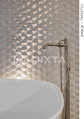 Metal faucet and shower in bathroom with hexagon tiles and white bath tub Metal faucet and shower in bathroom with hexagon tiles and white bath tub 74033711
