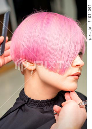 Hairdresser makes short pink hairstyle Hairdresser makes short pink hairstyle 74034092