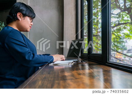 Student using laptop next to window with beautiful garden view Student using laptop next to window with beautiful garden view 74035602
