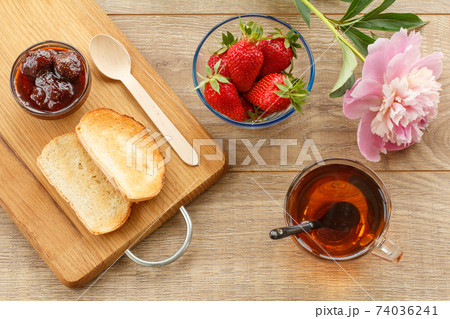 Cup of tea, homemade strawberry jam in bowl, fresh berries with toast on wooden background. Cup of tea, homemade strawberry jam in bowl, fresh berries with toast on wooden background. 74036241