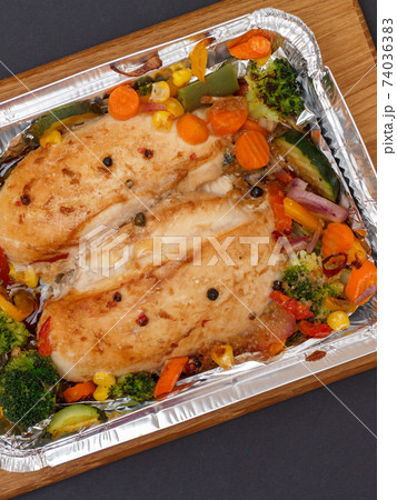 Baked chicken breasts or fillet in metal container with vegetables. Baked chicken breasts or fillet in metal container with vegetables. 74036383