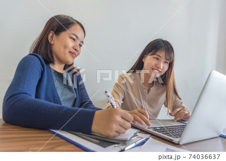 Young office ladies working on laptop during business discussion 74036637