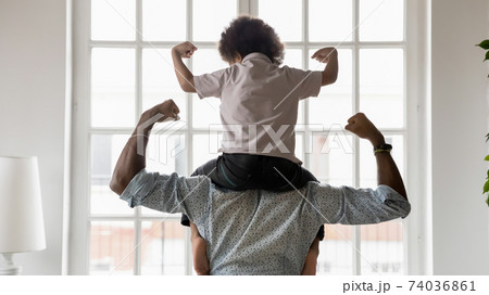 Rear view African American father and little son showing biceps 74036861