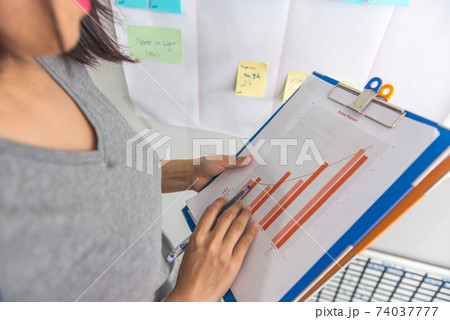Woman holding sales report and pointing at the highest point Woman holding sales report and pointing at the highest point 74037777