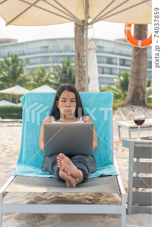 Woman using laptop while relaxing on the beach 74037859