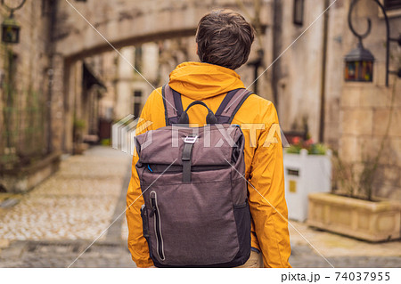 Young man tourist walks down the street in a European city after the end of COVID-19 coronavirus. quarantine is over 74037955