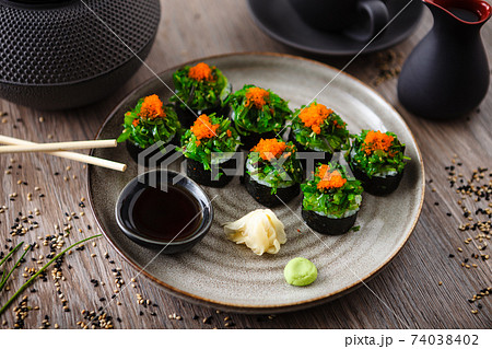 Sushi maki rolls with crab, seaweed salad and flying fish roe on a plate with chopsticks, soy sauce, wasabi and ginger. Japanese traditional seafood served for lunch in modern gourmet restaurant Sushi maki rolls with crab, seaweed salad and flying fish roe on a plate with chopsticks, soy sauce, wasabi and ginger. Japanese traditional seafood served for lunch in modern gourmet restaurant 74038402