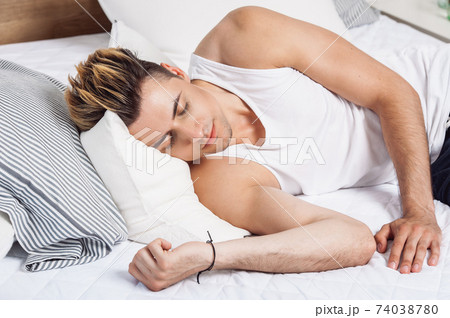 Man sleeping on a white pillow and a mattress on a wooden bed. Concept of comfortable sleep. orthopedic mattress and pillow Man sleeping on a white pillow and a mattress on a wooden bed. Concept of comfortable sleep. orthopedic mattress and pillow 74038780