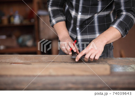 Carpenter, joiner is working in the workshop. Man at work on wood.Image of mature carpenter in the workshop,furniture making concept. Carpenter, joiner is working in the workshop. Man at work on wood.Image of mature carpenter in the workshop,furniture making concept. 74039643