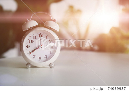 Selective focus of alarm clock show 8 o'clock or 8 a.m. on table with nature bokeh background. Time in life. Selective focus of alarm clock show 8 o'clock or 8 a.m. on table with nature bokeh background. Time in life. 74039987