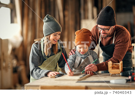 Happy family working together in carpentry workshop 74040343