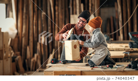 Dad and kid assembling wooden bird house Dad and kid assembling wooden bird house 74040347