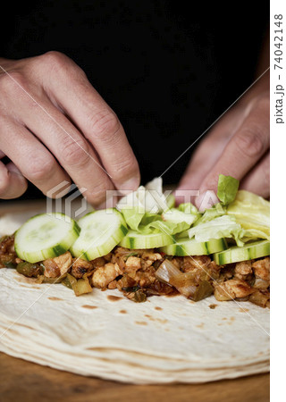 closeup of a man preparing a durum or a burrito 74042148