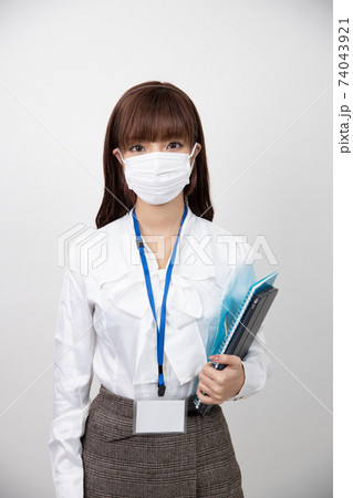 マスクをしてノートを持ち正面を見る若い女性の写真素材