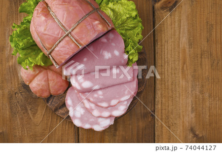 big Italian Whole block of mortadella on a wooden plate. Traditional big sausage and black pepper 74044127
