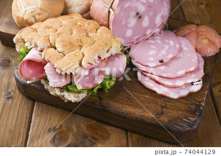 Big Italian Mortadella. Lunch from Focaccia with rosemary with mortadela and green salad 74044129