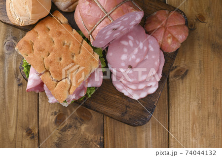 Big Italian Mortadella. Lunch from Focaccia with rosemary with mortadela and green salad 74044132