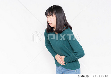 白背景の前に立って、お腹に手を当てている女性 74045918