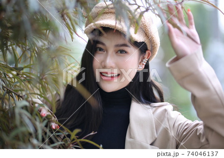 Portrait of young beautiful woman in winter clothes. while posing on snow background. Outdoor close-up photo of female model with romantic smile chilling in park in winter. 74046137