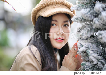 Portrait of young beautiful woman in winter clothes. while posing on snow background. Outdoor close-up photo of female model with romantic smile chilling in park in winter. 74046146