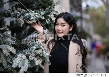 Portrait of young beautiful woman in winter clothes. while posing on snow background. Outdoor close-up photo of female model with romantic smile chilling in park in winter. 74046151