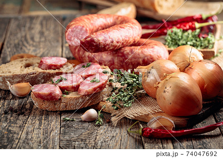 Sausage with bread and spices on a old wooden table. Sausage with bread and spices on a old wooden table. 74047692
